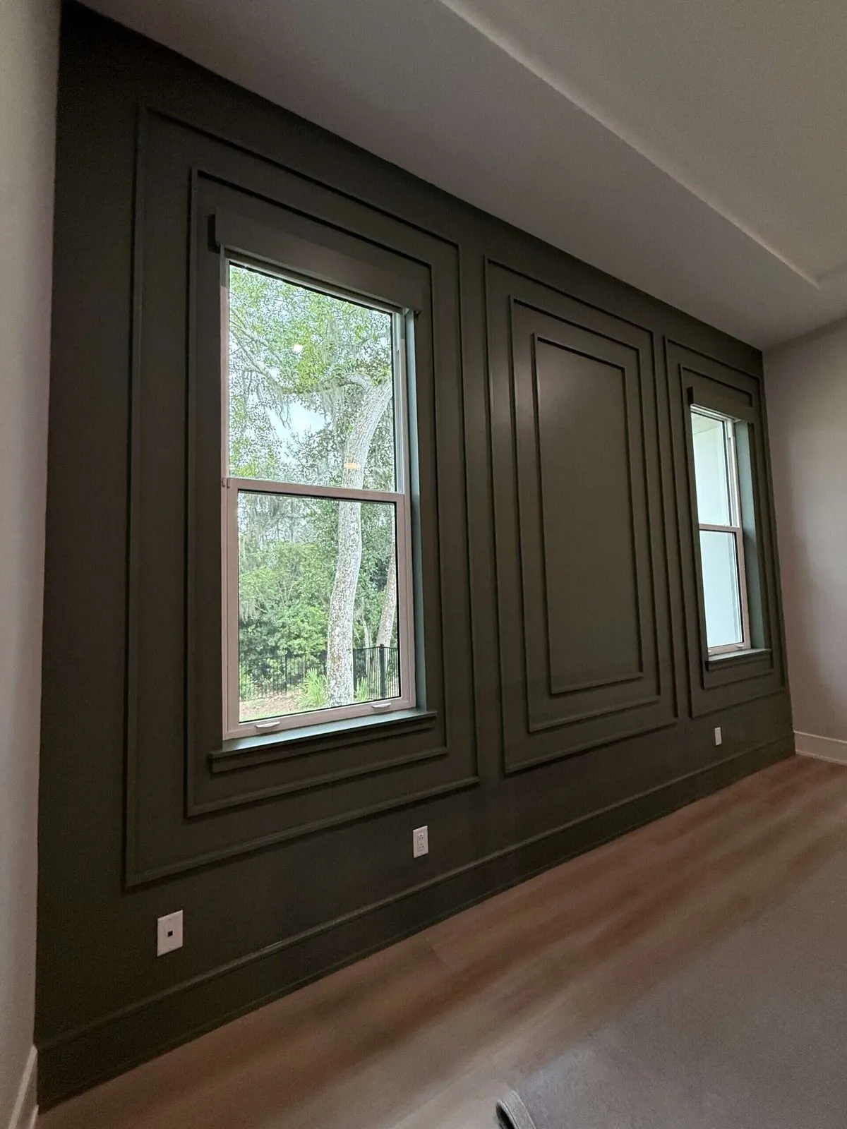 Dark painted picture-frame molding accent wall around two windows