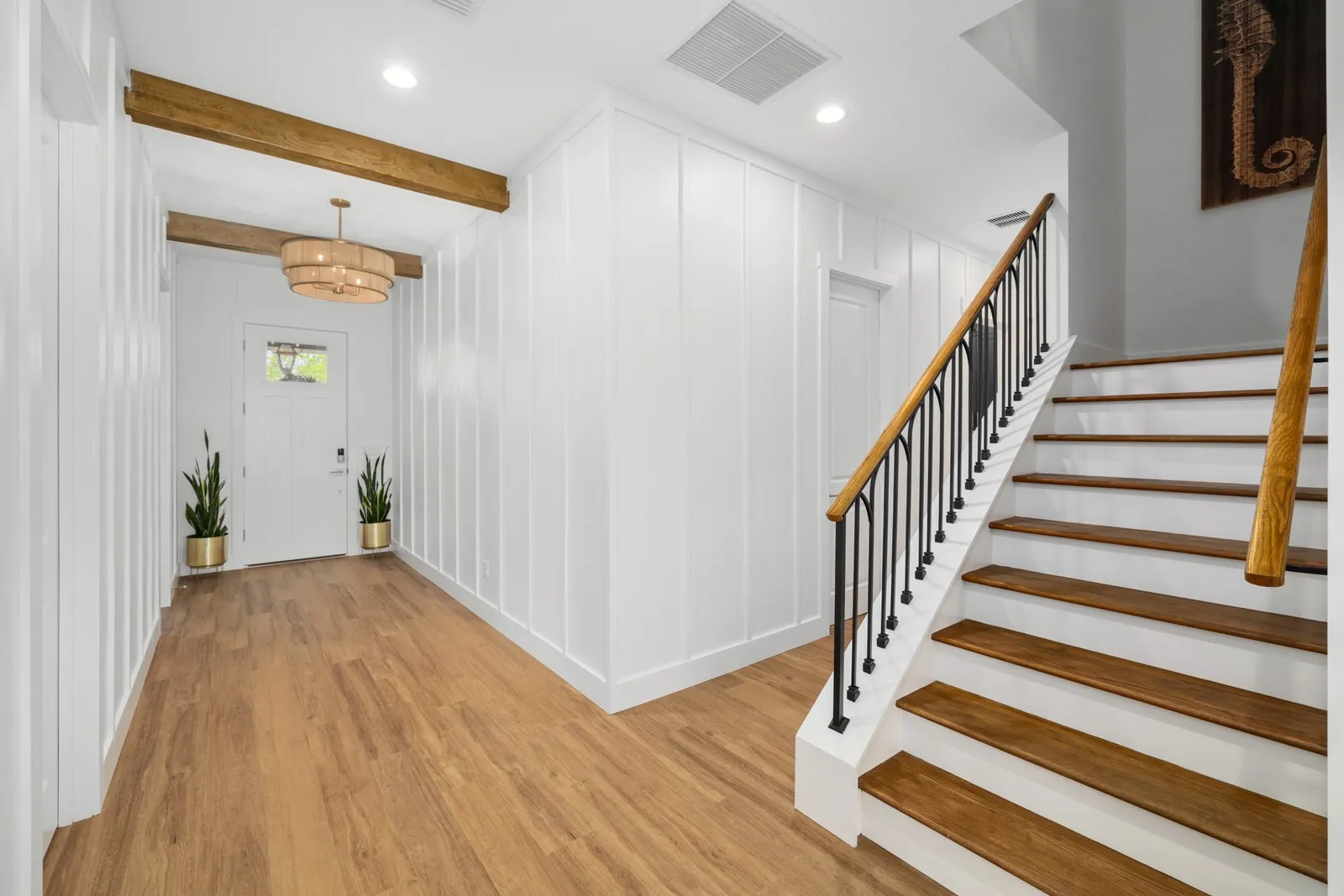 White board and batten walls in an entry hall with a staircase and wood beams