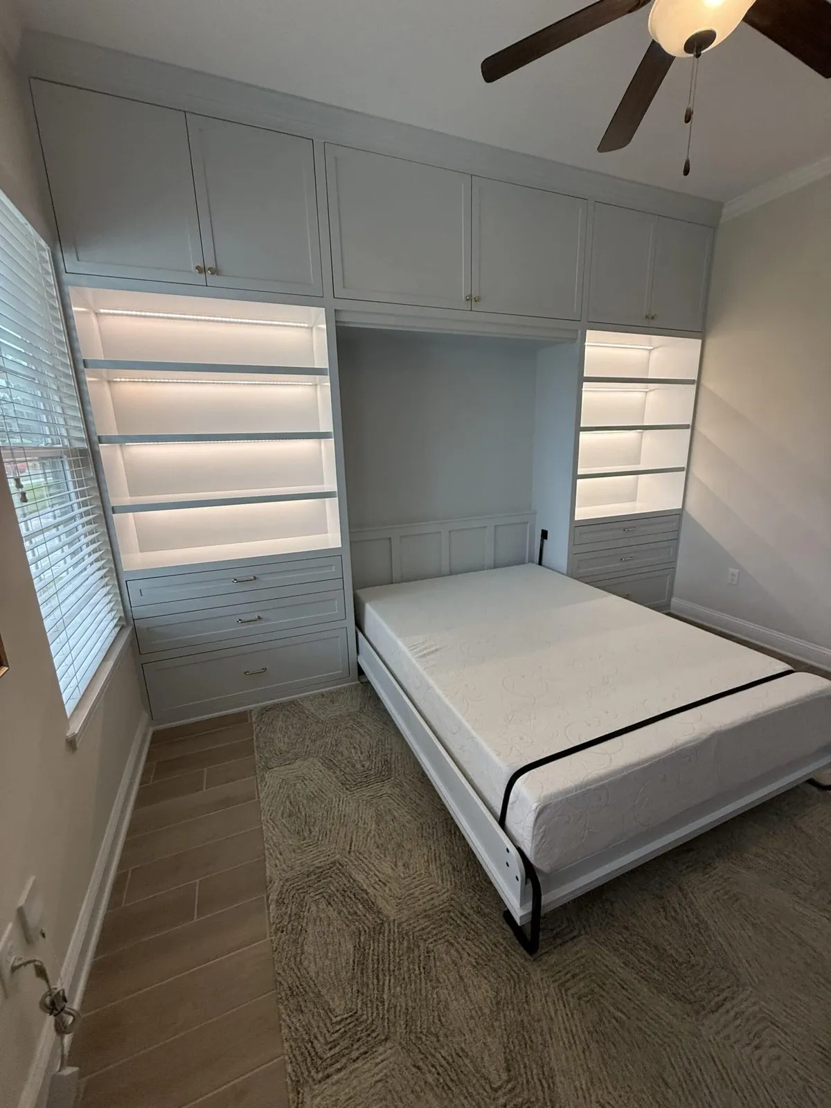 White Murphy bed built into a wall with lighted shelving in Ponte Vedra