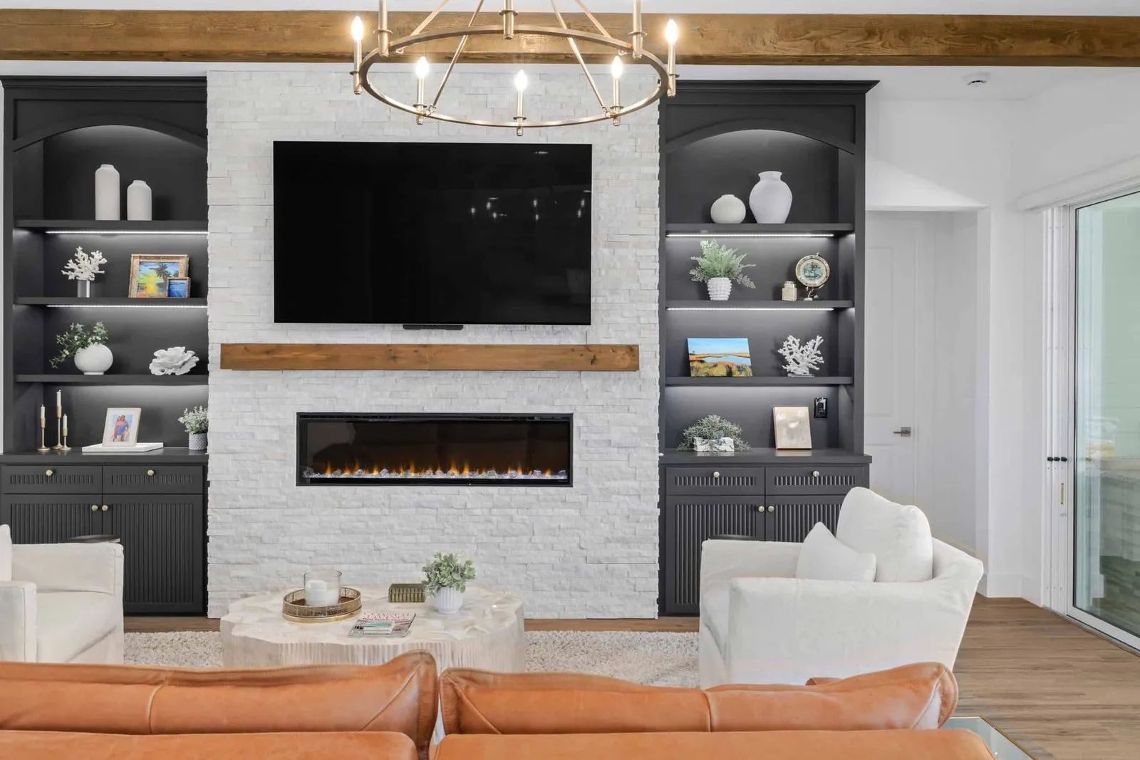 White stacked stone electric fireplace wall with dark built-in shelving and a mounted TV in St. Augustine